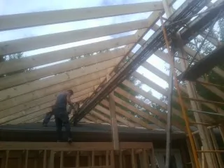 Rafters going up over a new addition with a worker on the wall in Lakewood