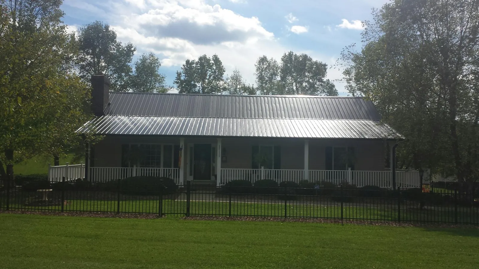 Gray metal roof on a brick ranch with a full width front porch — Gutter Guard Installation work by our crew in Lakewood